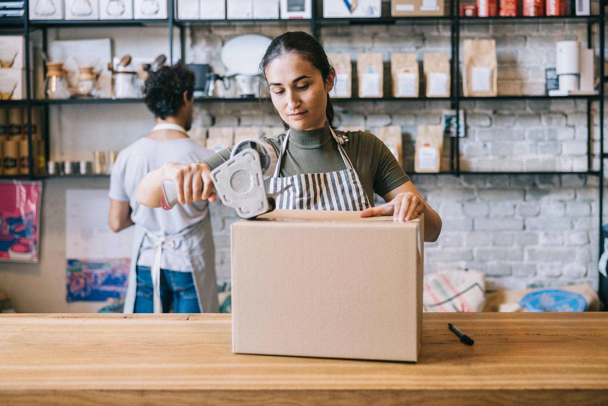 Person taping a shipping box at a counter