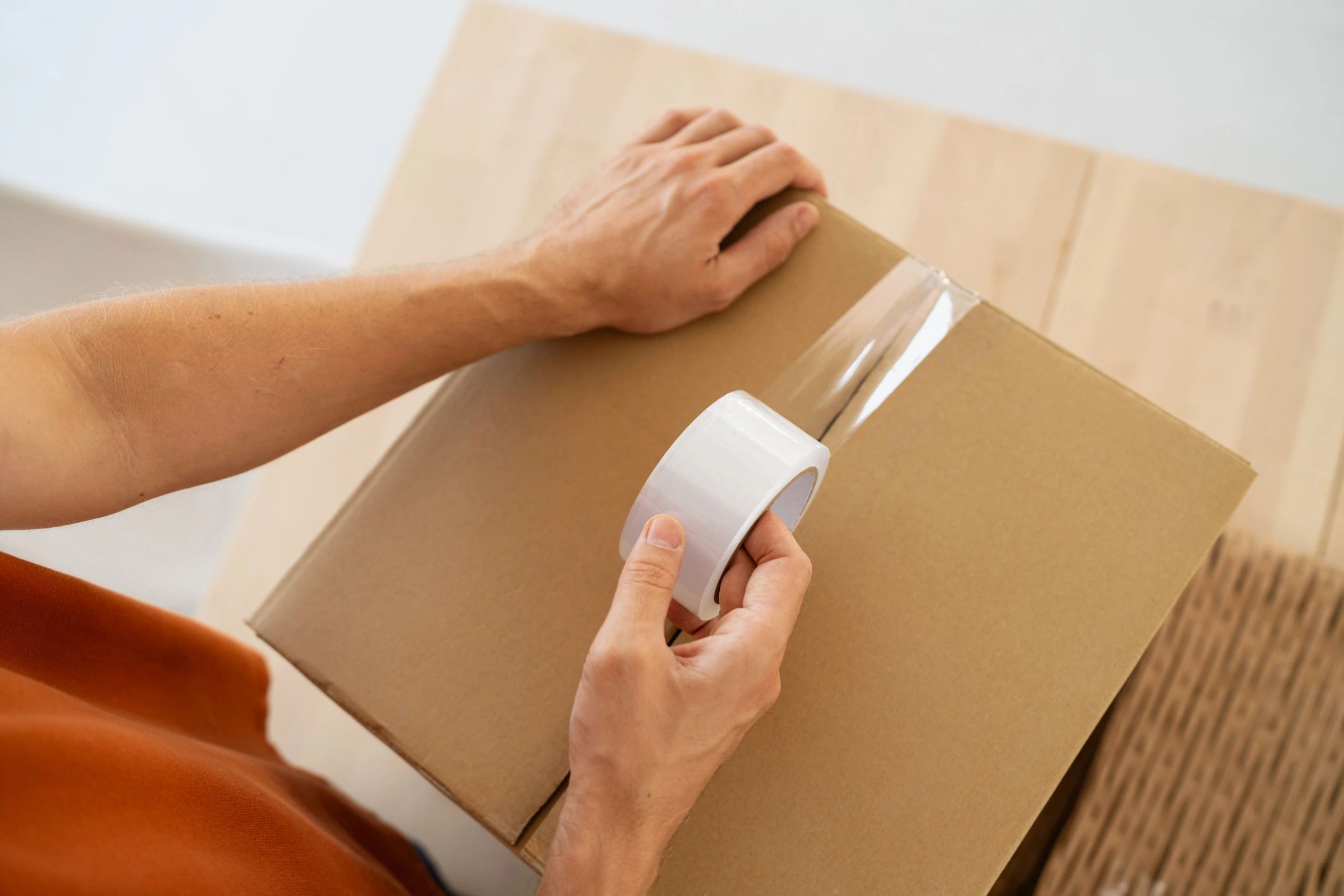Person sealing a cardboard box with clear tape